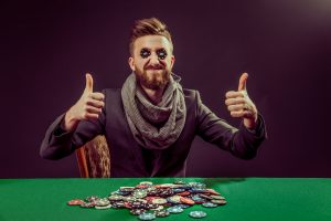portrait of successful pocker player with thumbs up smiling while putting black chips in eyes
